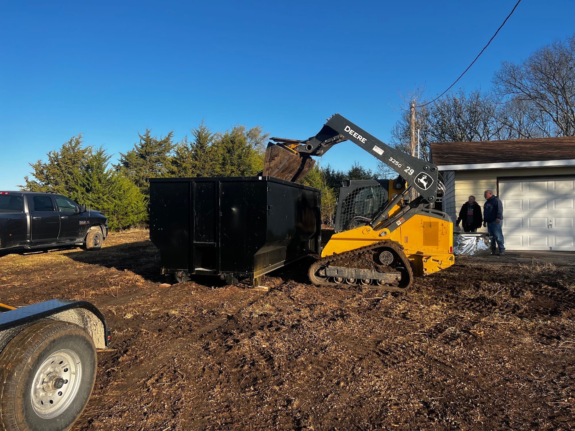 Dumpster being loaded by a skid steer on a job site