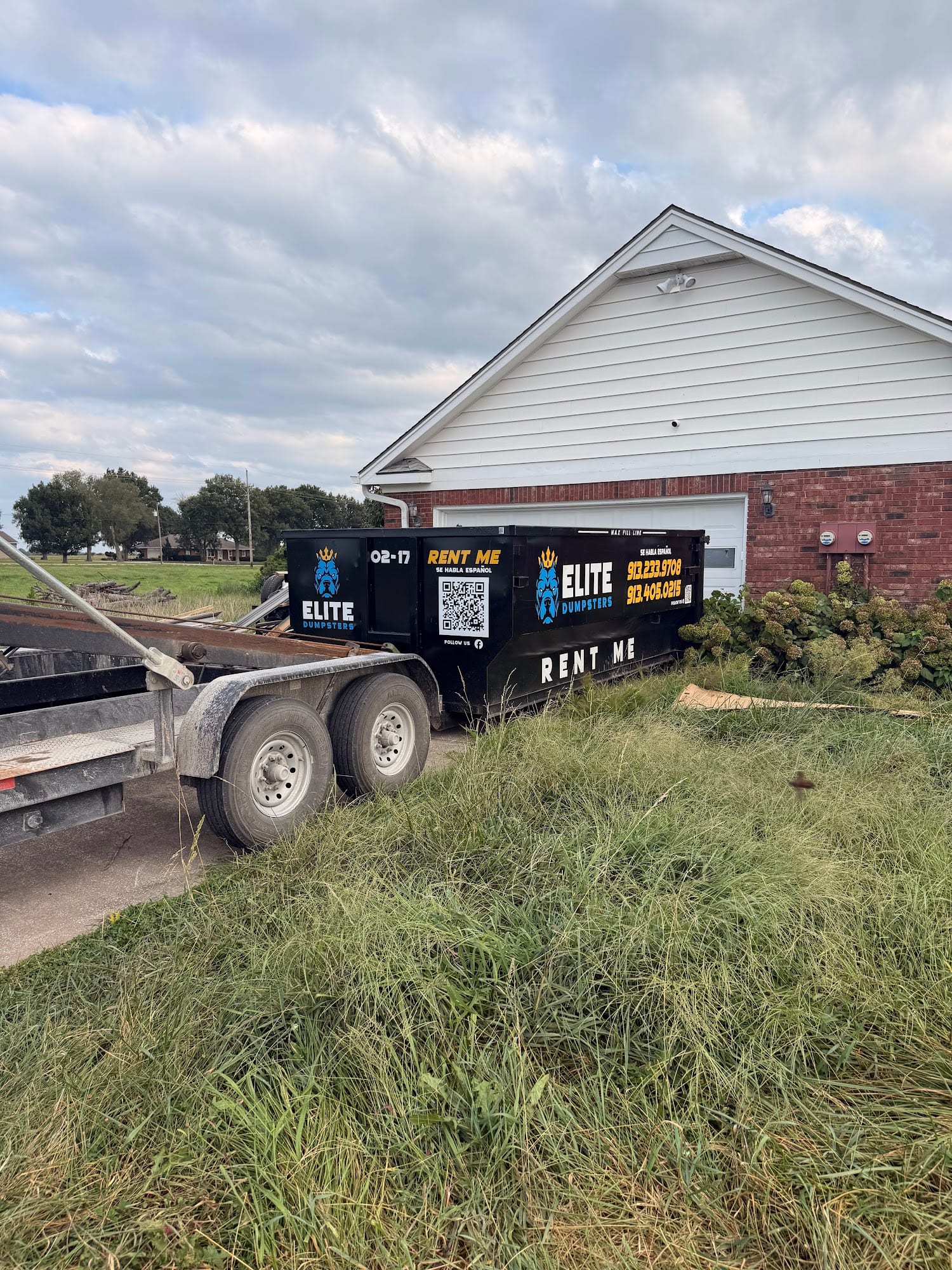 Dropping off an Elite dumpster beside a house