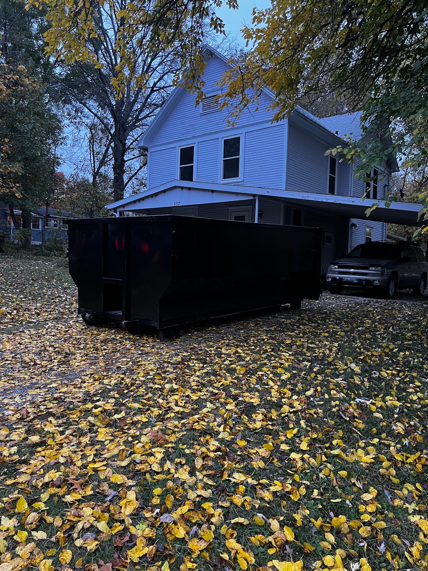 Roll-off dumpster on a leafy driveway